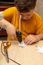 A boy glues snowflakes on a Christmas tree