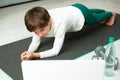 The boy goes in for sports at home online. The child does exercises in the room