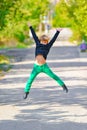 A boy in green pants jumps up for joy in the park on a walk