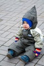 A boy in green snowsuit sitting on paving stone Royalty Free Stock Photo