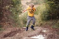 Boy in gumboots jumps into the puddle