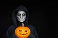 Boy with Halloween makeup holding Jack O`Lantern pumpkin on black background Royalty Free Stock Photo