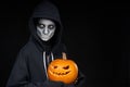 Boy with Halloween makeup holding Jack O`Lantern pumpkin on black background Royalty Free Stock Photo