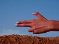 Boy hand on gun shape presented on blue sky