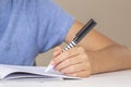 Boy hand holding pen in left hand and writing in a notebook, doing homework. Left Handers Day Royalty Free Stock Photo