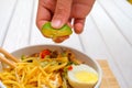 Boy hand squeezing lime on Malay Mee Rebus in the bowl with chopsticks on white table This dish is made of noodles ,vegetable,egg Royalty Free Stock Photo