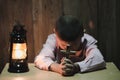 Boy hands holding a holy cross praying to God In the dark and with the lamp beside, Child Praying for God Religion Royalty Free Stock Photo