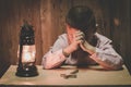 Boy hands praying with a holy cross In the dark and with the lamp beside, Child Praying for God Religion Royalty Free Stock Photo