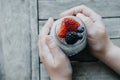 Boy hands with Pudding with chia seeds, yogurt and fresh fruits: Strawberries, blueberries and blackberries in glass jars on wood Royalty Free Stock Photo