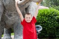 Boy hanging on elephant tusks sculpture