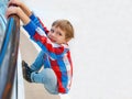 Boy is hanging on the railing of the bridge, child playing in a park