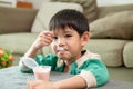 A boy happily uses a spoon to scoop up yogurt