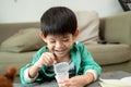 A boy happily uses a spoon to scoop up yogurt