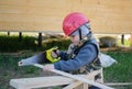 boy in hard hat with a handsaw sawing a wooden Board Royalty Free Stock Photo