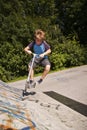 Boy has fun scooting with push scooter at the skatepark Royalty Free Stock Photo