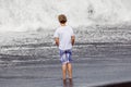 Boy has fun in the spume at the black volcanic beach