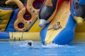 Boy has into pool after going down water slide during summer. little boy sliding down water slide and having Royalty Free Stock Photo