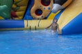 Boy has into pool after going down water slide during summer. little boy sliding down water slide and having Royalty Free Stock Photo