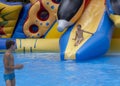 Boy has into pool after going down water slide during summer. little boy sliding down water slide and having Royalty Free Stock Photo