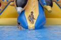 Boy has into pool after going down water slide during summer. little boy sliding down water slide and having Royalty Free Stock Photo