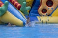 Boy has into pool after going down water slide during summer. little boy sliding down water slide and having Royalty Free Stock Photo