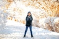 Boy in hat and scarf stands near the tree with snow and has some snoflakes in his hands. Christmas New Year mood. Winter time. Sno