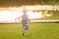 A boy in a hat at sunset plays with scoop-net outdoors on a summer day. Summer outdoor activities for children. Royalty Free Stock Photo