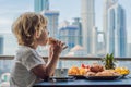 The boy is having breakfast on the balcony. Breakfast table with coffee fruit and bread croisant on a balcony against