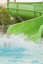 Boy is having fun, while spending time in the aquapark. He is sliding down the water slide making a numerous splashes. vertical Royalty Free Stock Photo