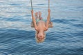 Boy having fun on swing over the sea. Child riding on swing upside down