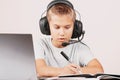 Boy in a headphones doing homework with notebook computer. Online learning, remote education at home Royalty Free Stock Photo