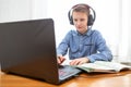 A boy in headphones in front of a computer does his homework. Distance learning in quarantine Royalty Free Stock Photo