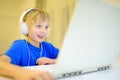 A boy in headphones plays a computer game or chats with a friend in a messenger. Child and gadgets. Little kids using modern