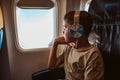 Boy with headphones sitting airplane, looking out of window. Concept of family beach summer vacation with kids. Royalty Free Stock Photo