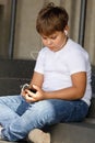 Young boy in headphones with smartphone listens to music in the park Royalty Free Stock Photo