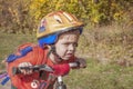 A boy in a helmet with a backpack rides a bicycle. He looks carefully ahead. Walk in the park Royalty Free Stock Photo