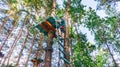 A boy in a helmet climbs the stairs to begin his journey through the adventure rope park. Active sports holiday ideas for children