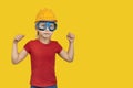 Boy in helmet construction and safety glasses on yellow background. Children like adults