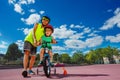 Boy help little brother to learn ride pushing bicycle in park