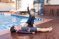 Boy helping drowning child girl in swimming pool by doing CPR.