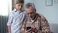 Boy helping grandfather to better understand smartphone, digital generation gap Royalty Free Stock Photo