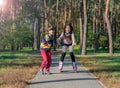 Boy helps the girl to roller-skate in the park. Brother supports Royalty Free Stock Photo