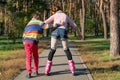 The boy helps the girl to roller-skate in the park. Brother supp