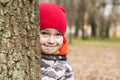 The boy hides behind a tree in the park. A child looks out from behind a tree, playing hide and seek on the street. Little boy is Royalty Free Stock Photo