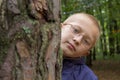 Boy is hiding behind a tree,Portrait of little boy peeking from behind tree,eye glasses Royalty Free Stock Photo