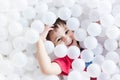 Boy hiding under white balls at the playground