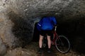 Boy hiker - mountainbiker in a sabdstone cave or dry water channel. Visiting of underground Royalty Free Stock Photo