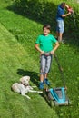 Boy and his father mowing the lawn and trimming the hedge Royalty Free Stock Photo