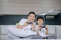 Boy and his father playing video game in bedroom Royalty Free Stock Photo