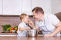 Boy and his father are preparing soup together in kitchen at home. Having fun Royalty Free Stock Photo